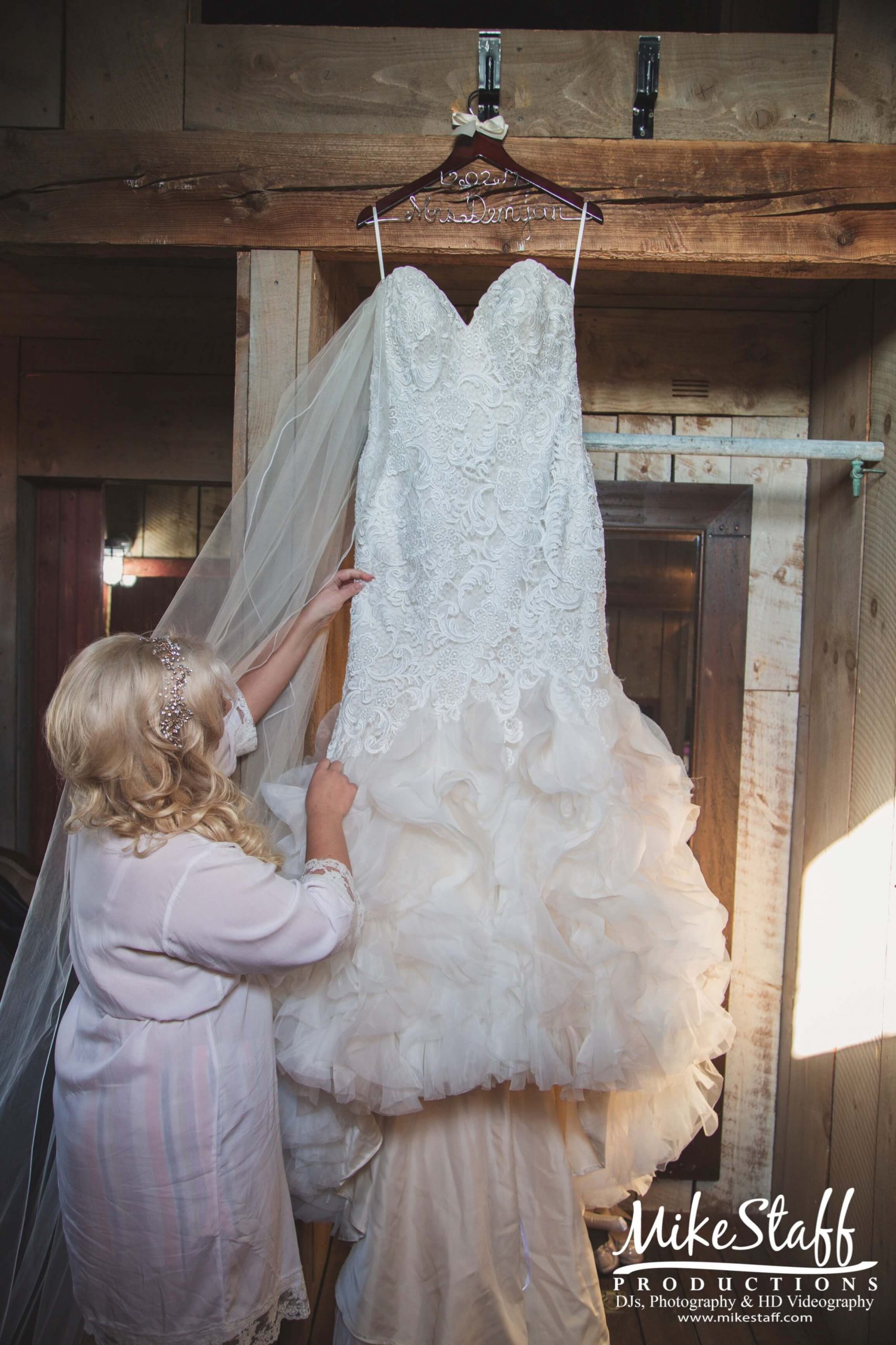 bride looking at dress hanging in barn