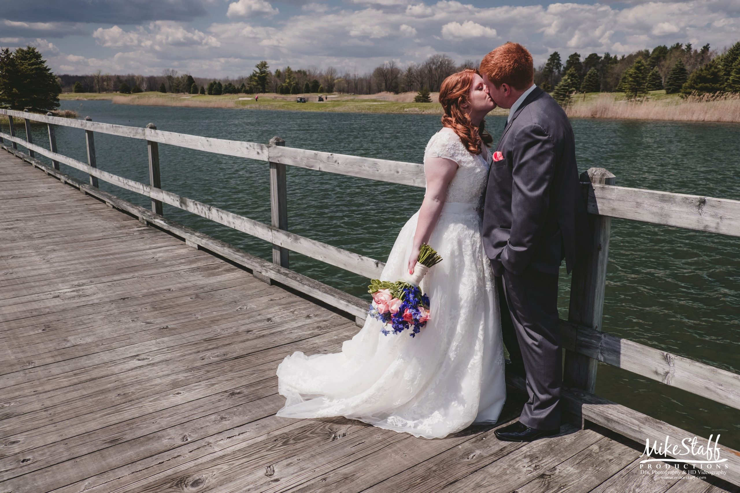 bride and groom kissing on bridge