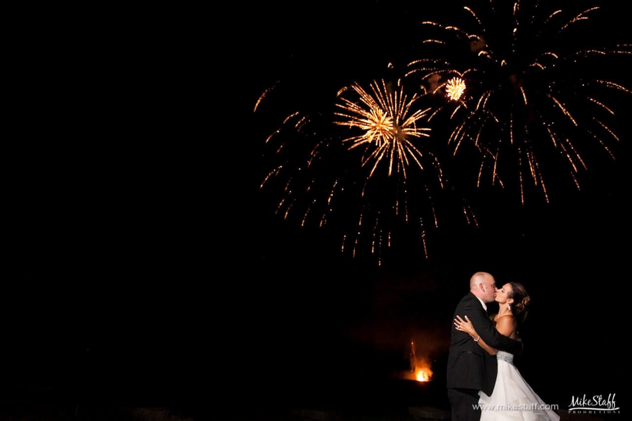 bride and groom kissing with fireworks