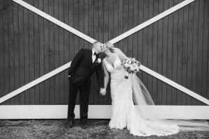 bride and groom kissing outside barn