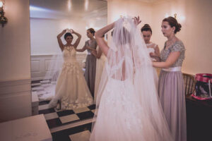 bride putting on veil with bridesmaids