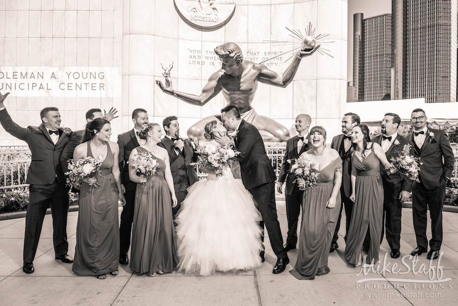 bride and groom kissing in detroit surrounded by bridal party