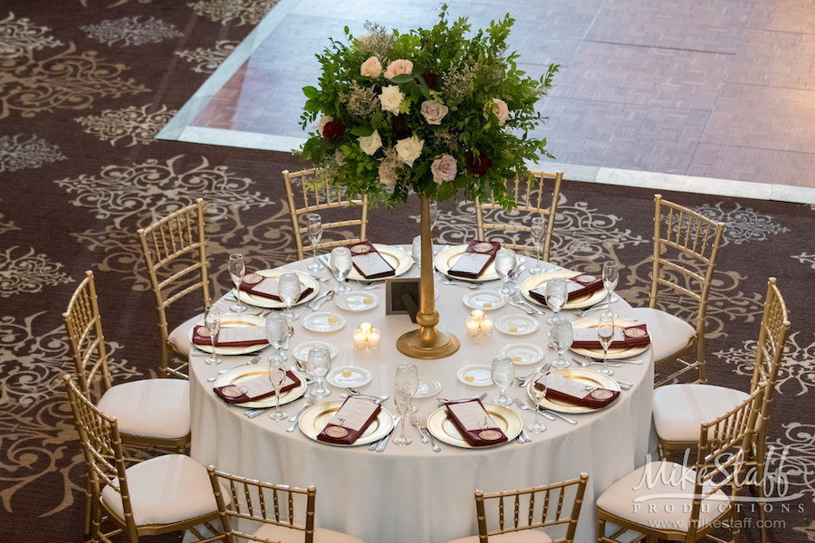 reception centerpiece with tall gold base and large floral arrangement