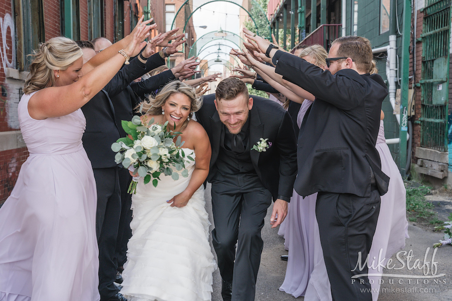 bride and groom running through bridal party