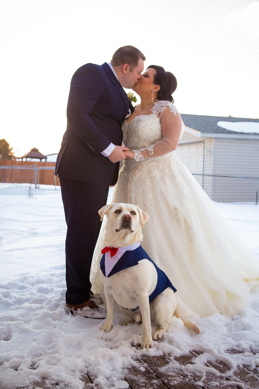 bride and groom kissing with dog sitting in front