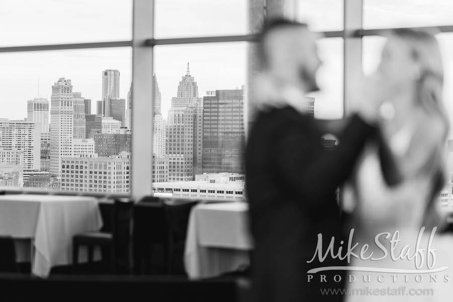 bride and groom dancing out of focus with detroit skyline