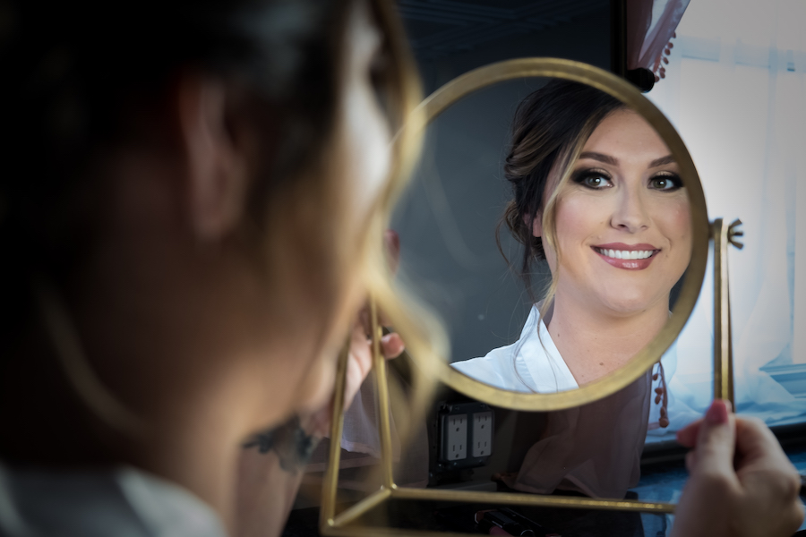bride looking in the mirror after getting her wedding makeup done