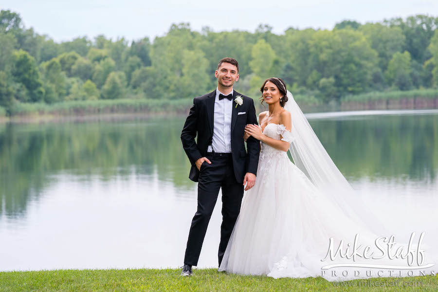 bride and groom standing by water