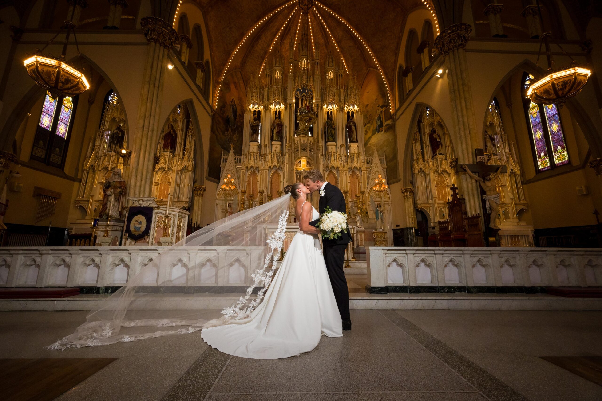 andrea-christopher-meadowbrook-country-club-wedding-dramatic-veil-kiss - Mike Staff Productions Romantic bride and groom kiss with flowing cathedral veil at Sweetest Heart of Mary Church